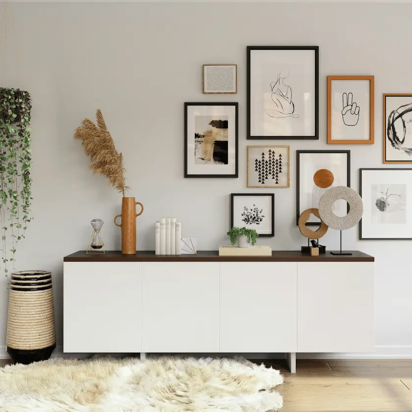 A modern living room features a white console table with dark wood top, decorated with a gallery wall of black and wood framed art, a large woven basket, and a cream-colored rug.