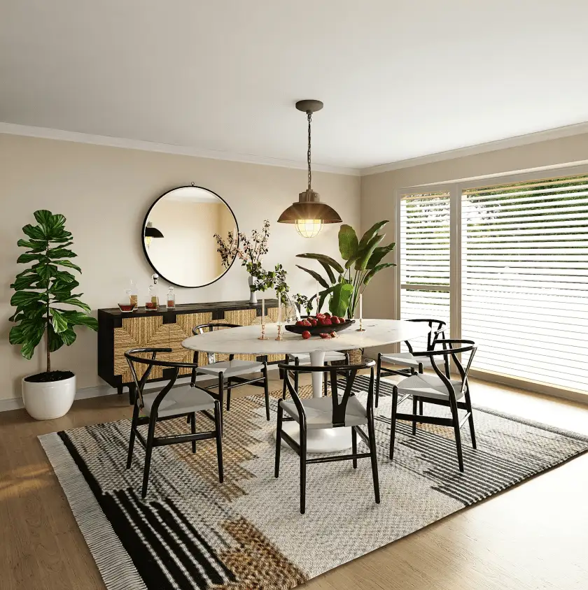 A modern dining room boasts an oval white table with wishbone chairs, a large round mirror above a woven buffet, and a vintage-style pendant light, all on a patterned rug.